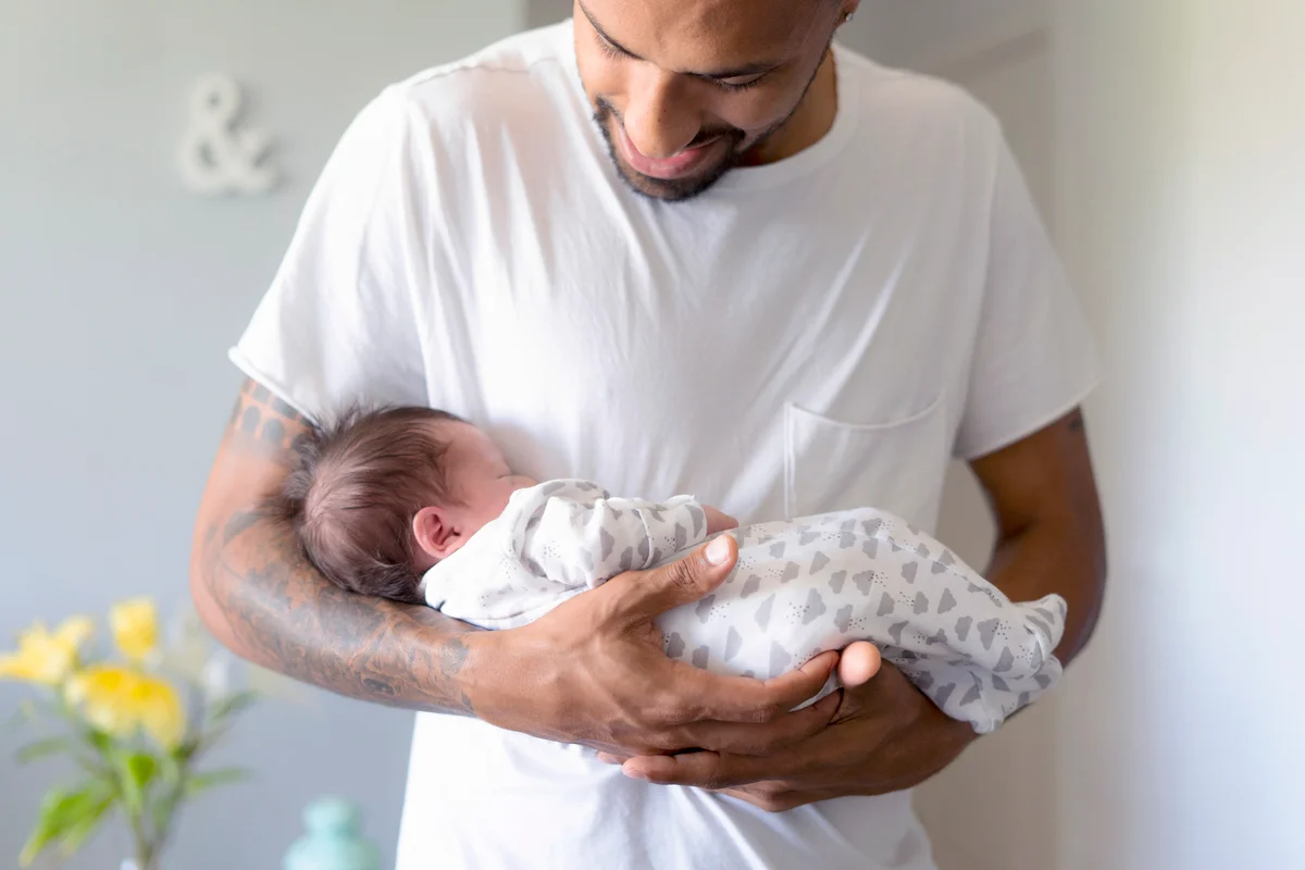 Father holding his sleeping newborn baby